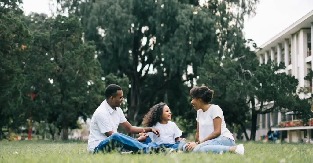 A happy black family enjoying quality time together outdoors in a lush green park.